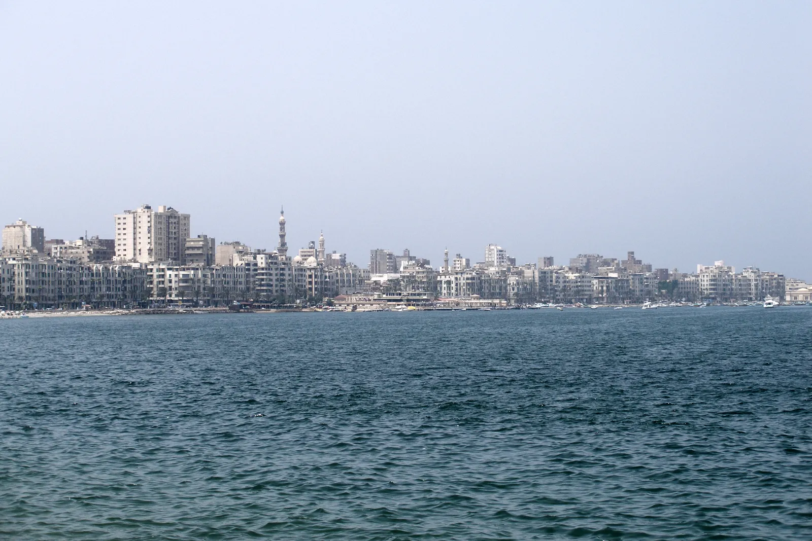 Alexandria's waterfront skyline of apartment buildings and a mosque minaret seen across the harbor.