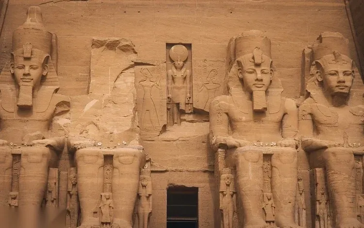 Wide aerial view of the Abu Simbel temple complex and surrounding village beside Lake Nasser.