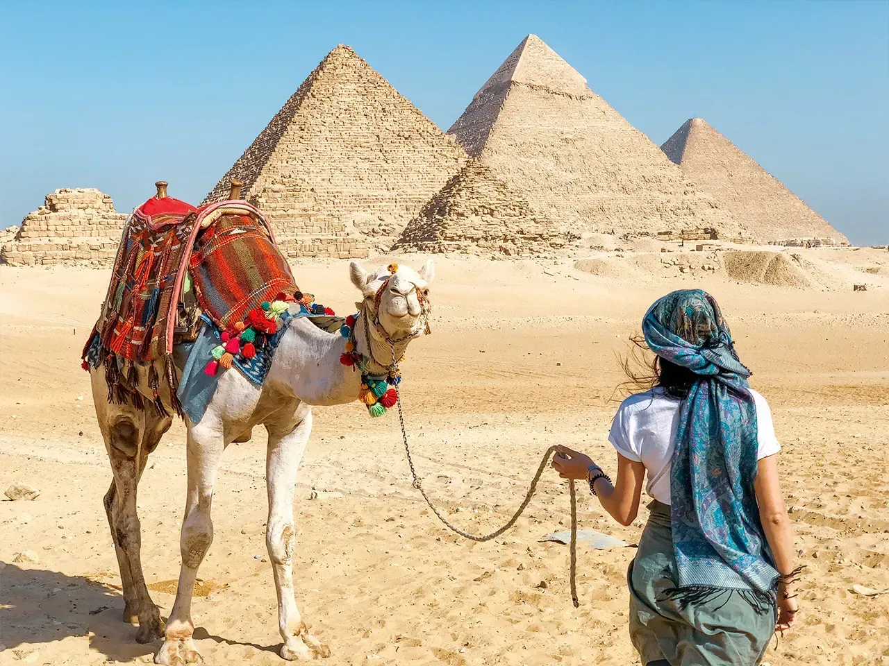 A wide view of the Pyramids of Menkaure and Khafre with the hazy skyline of Cairo visible in the background.