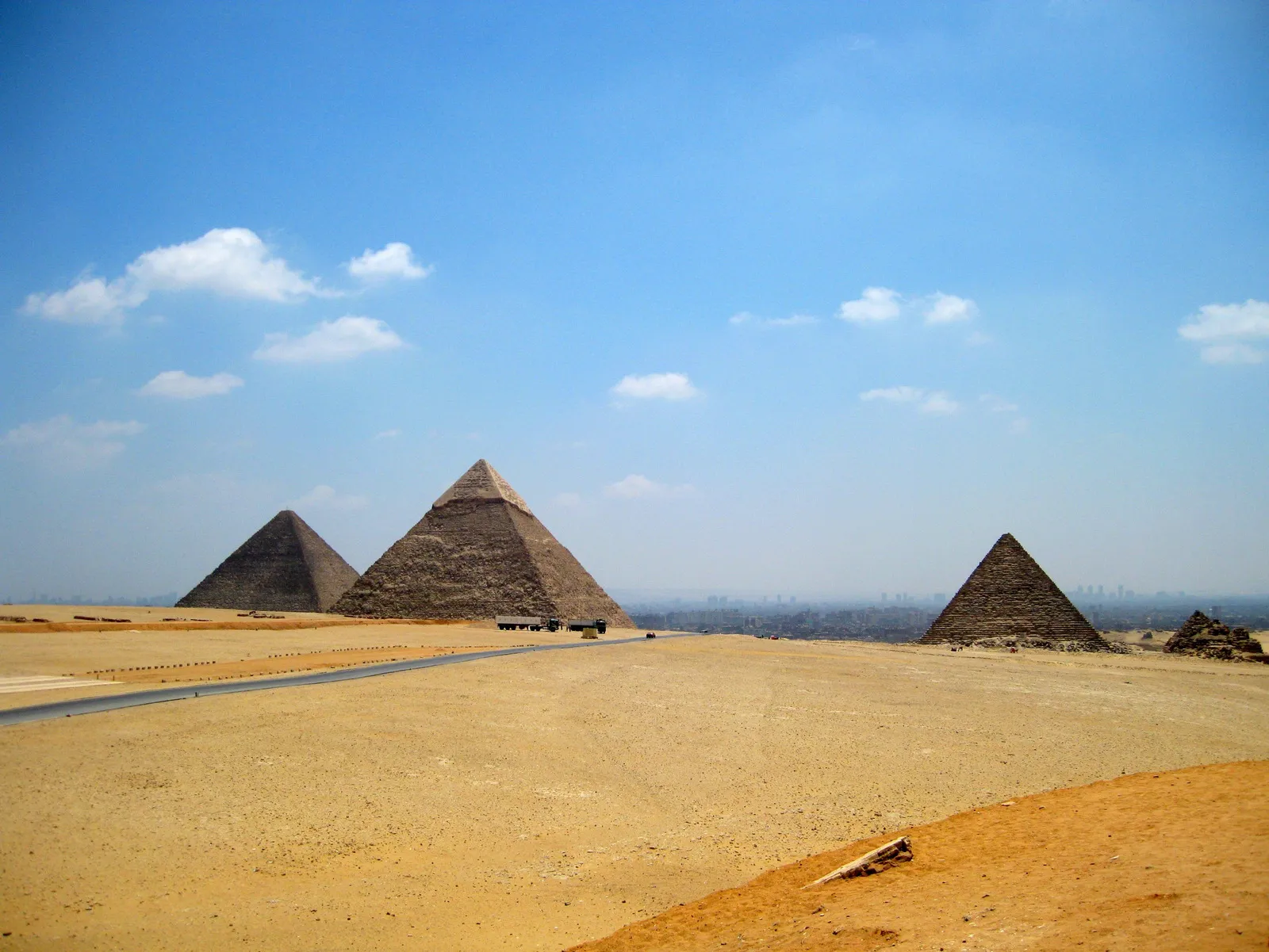 A woman forms a heart shape with her hands, framing the distant Giza pyramids in the gap between her fingers.