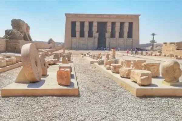 Stone pathway leads to the imposing facade of Dendera Temple with rows of Hathor-headed columns.
