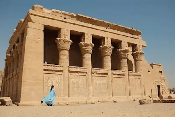 Close-up of carved stone columns topped with Hathor-head capitals along the temple's front wall.