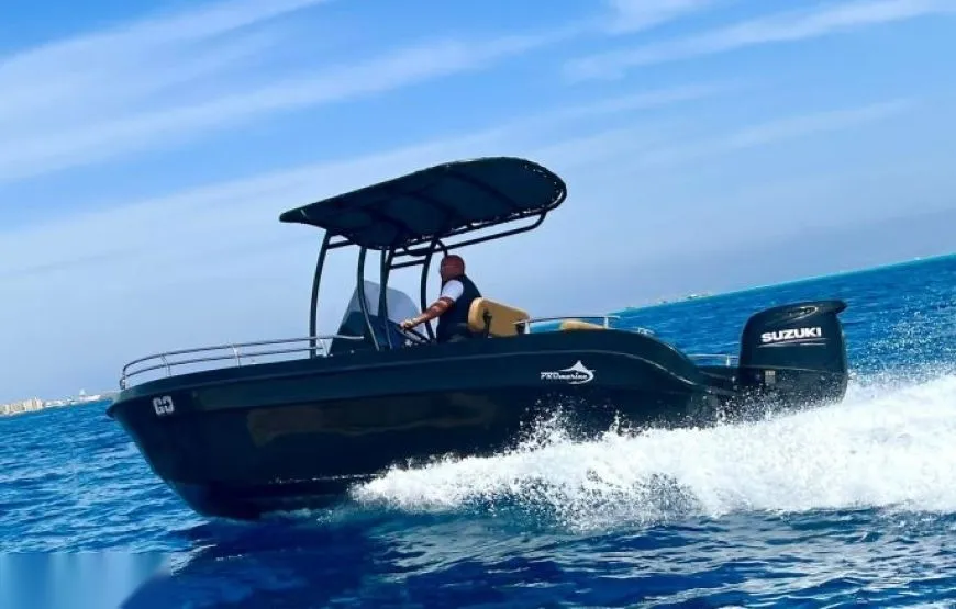 Aerial view of a small speedboat with passengers aboard, seen from the ladder of another boat, floating over turquoise water.