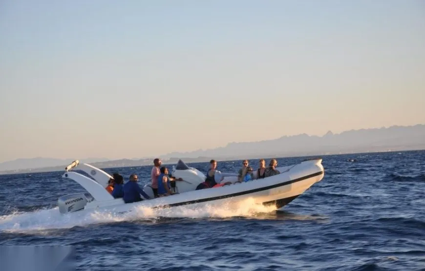 Group of passengers eating a meal aboard a moving speedboat with its wake visible behind.