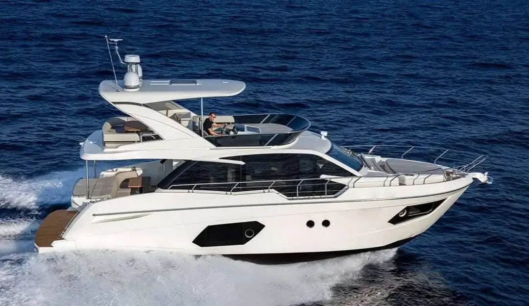 Yacht interior lounge and dining seating area with sea views through large windows.