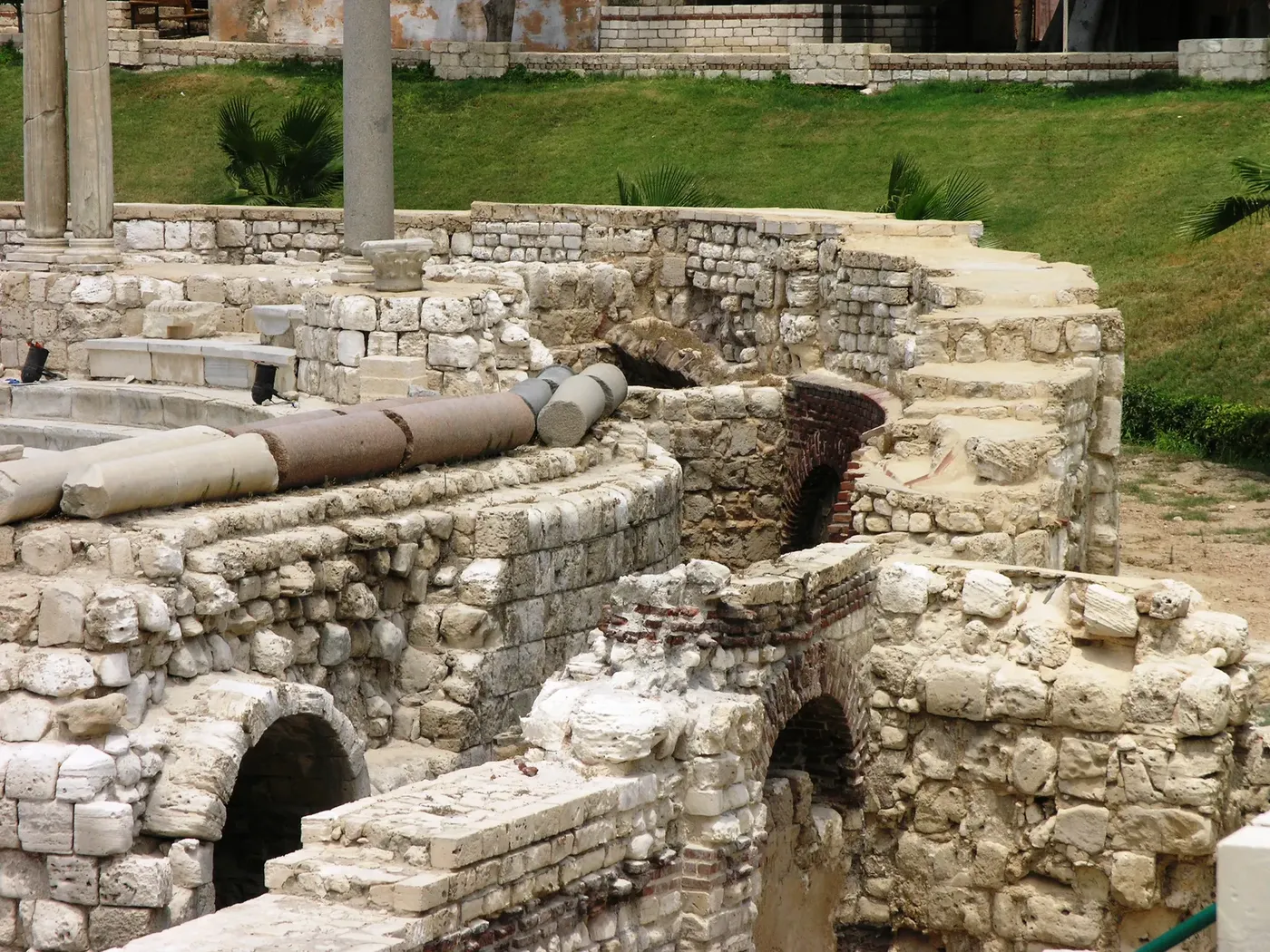 Elevated view of the Roman amphitheater's curved stone tiers surrounded by excavated brick and stone ruins.