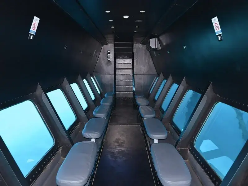 Empty rows of seats face large underwater viewing windows inside the cabin of the Royal Seascope semi-submarine.