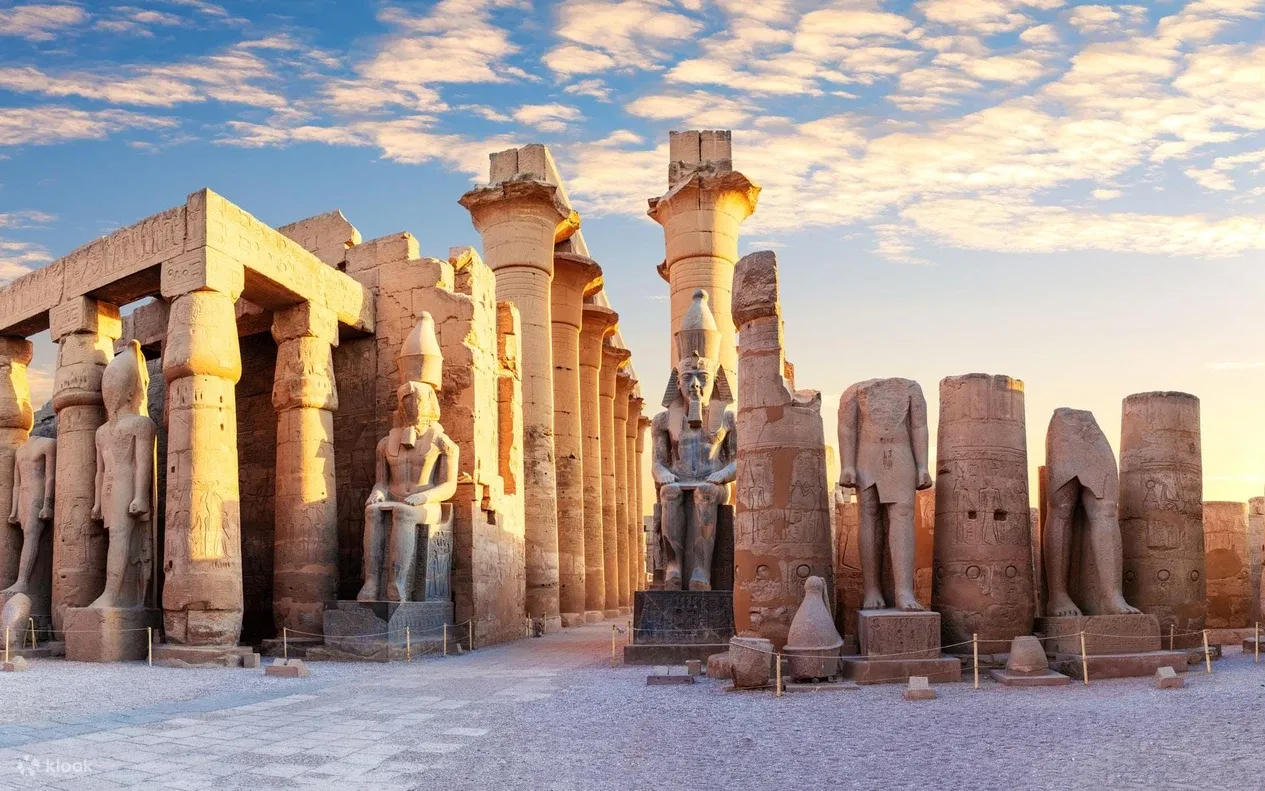 Colossal statues of Ramesses II stand among towering papyrus columns in the peristyle court of Luxor Temple.