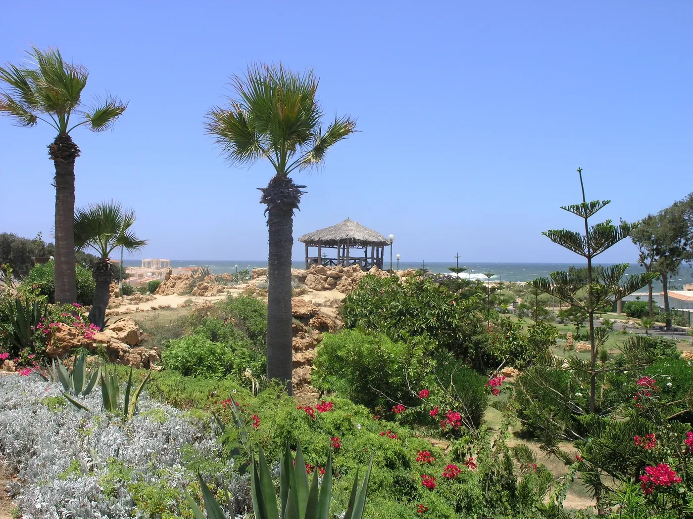 Elevated view of the full palace complex and grounds with the Mediterranean coastline visible in the background.