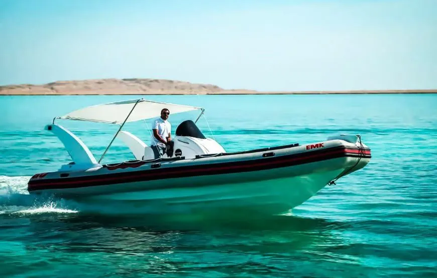 A group of passengers eats lunch at a small table on the back of a speedboat while it cuts through the water, leaving a wake behind.