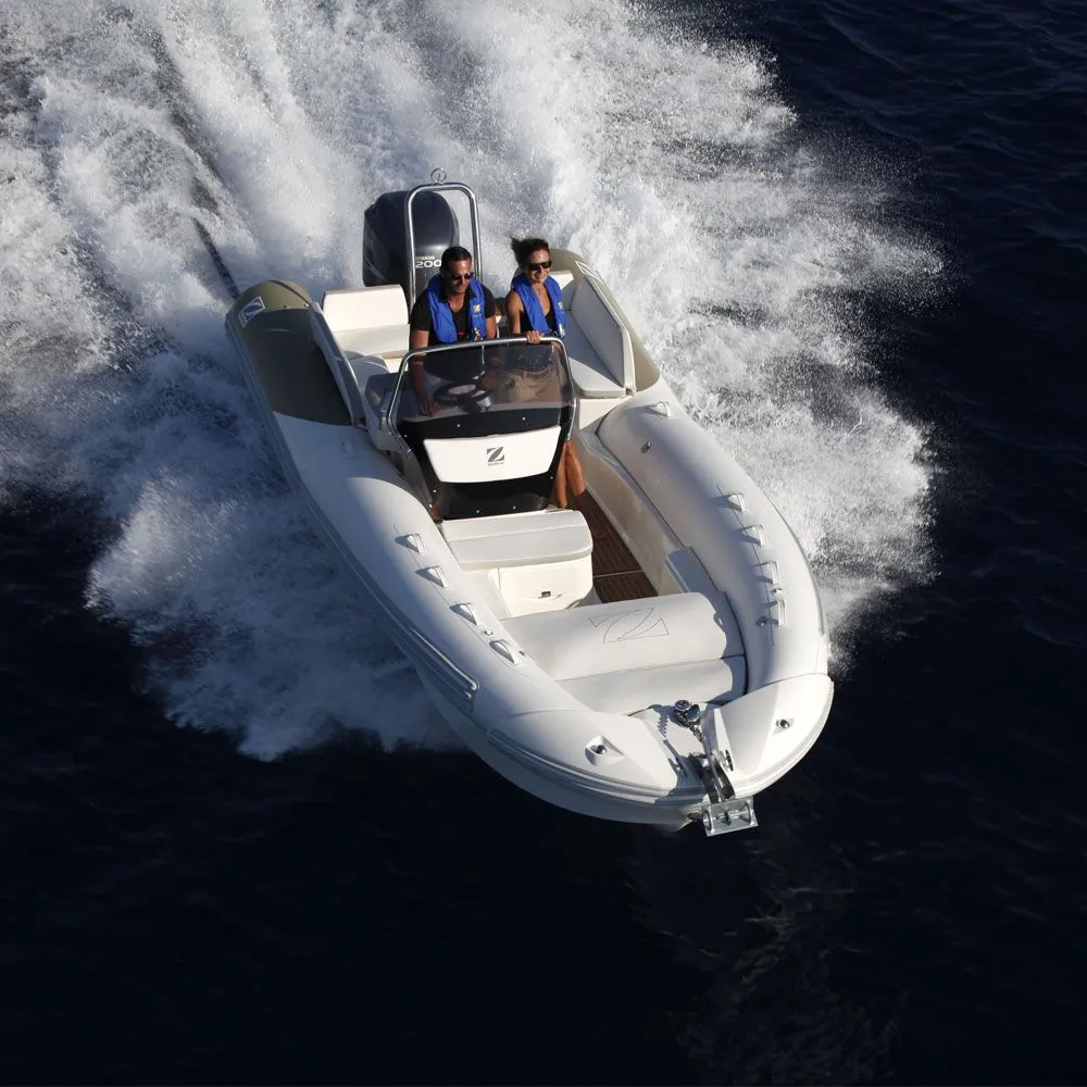 Two couples relax on the cushioned seating of a moving speedboat, drinking cocktails beside a tray of fresh pineapple and fruit, with a coastline in the background.
