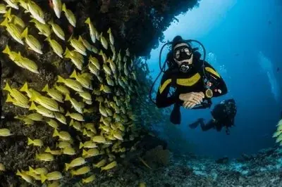 Instructor supporting a student diver as she practices mask and regulator skills at the surface of a swimming pool.