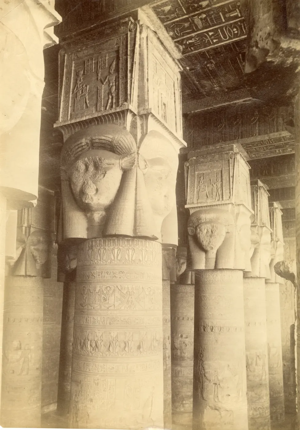 Tour group posing and waving in front of the Hathor-headed columns on the facade of Dendera Temple.