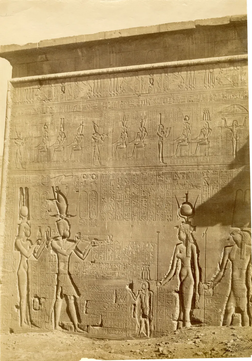 Ancient stone sarcophagi and carved fragments laid out in the temple courtyard in front of the Dendera Temple building.