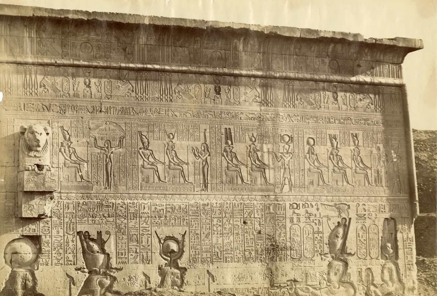 Small group of visitors standing in front of the Hathor-headed column facade of Dendera Temple.