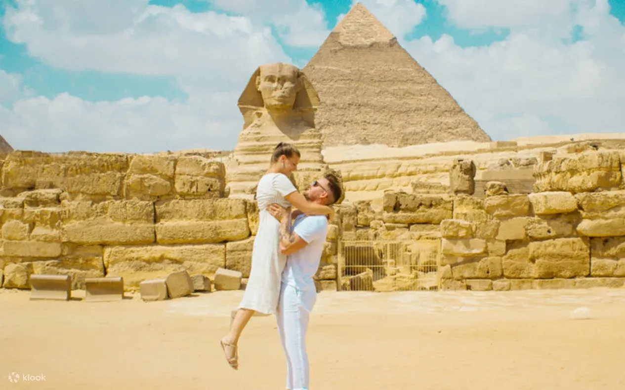 A family of three posing with a seated camel in front of the Giza pyramids.