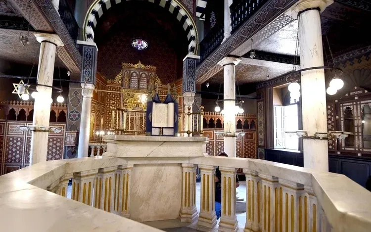 Interior of Ben Ezra Synagogue in Coptic Cairo, showing the marble bimah platform and the ornate wooden Torah ark.