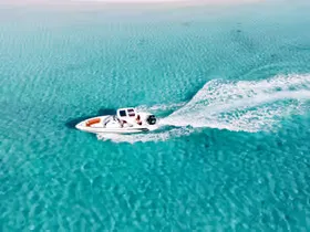 Aerial view of a speedboat cutting through turquoise water and leaving a curved white wake.