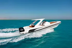 Side view of a speedboat with passengers cruising across calm turquoise sea.