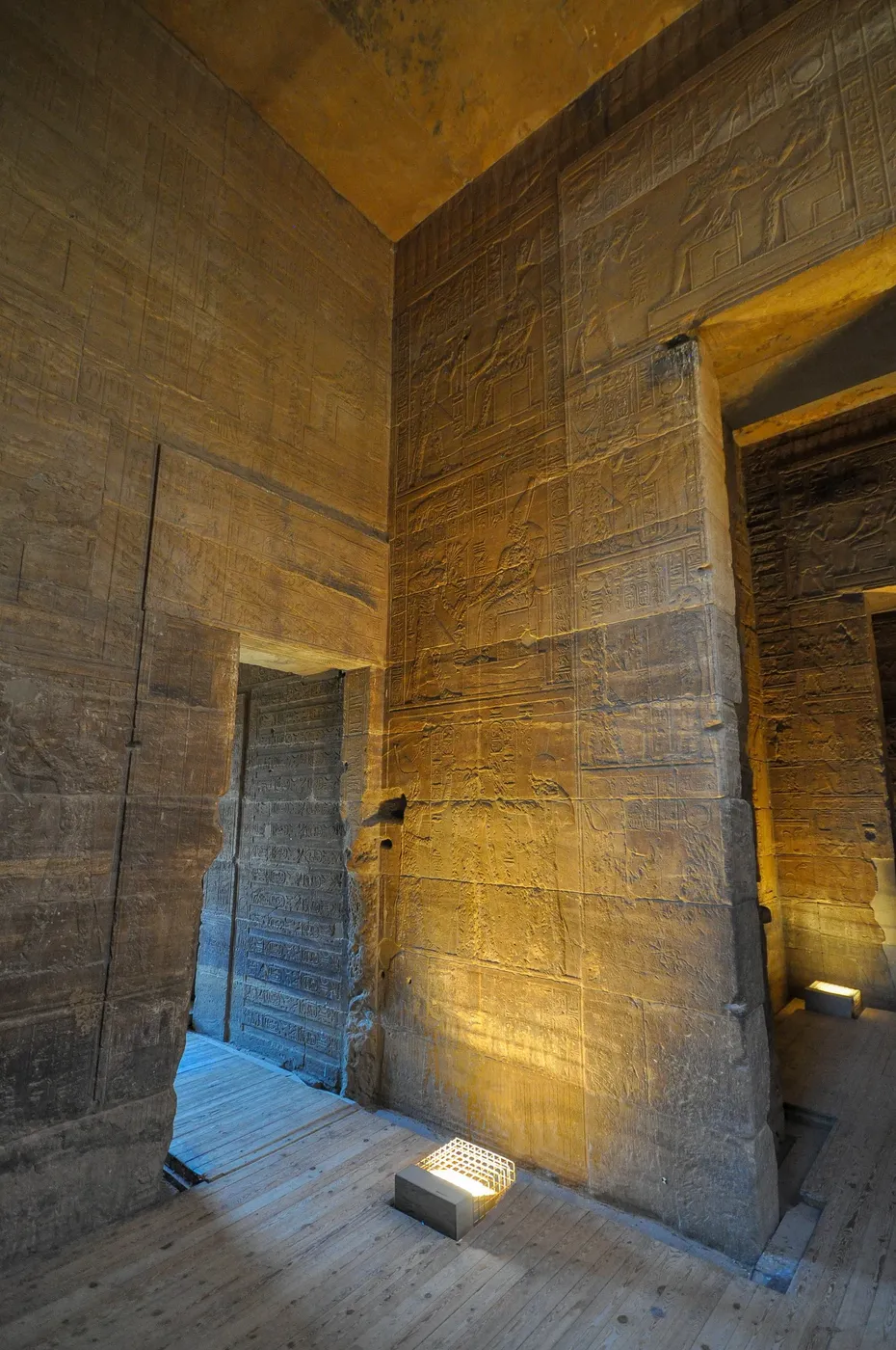 A large group of tourists poses for a photo in front of the massive carved pylon entrance of Philae Temple.