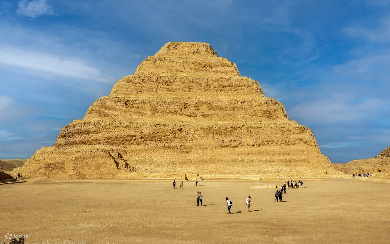 Woman posing solo with arms raised in front of the Step Pyramid of Djoser at Saqqara