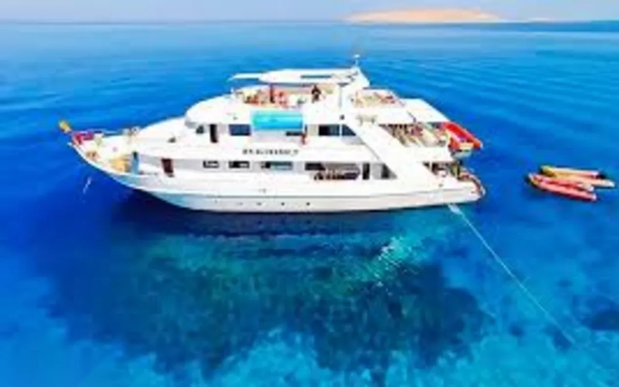 Split-level photo of a snorkeler swimming over a coral reef, with dive boats anchored on the surface above.