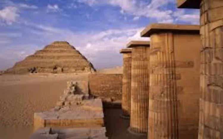 View of the Step Pyramid of Djoser across the desert, framed by a row of stone columns in the foreground.