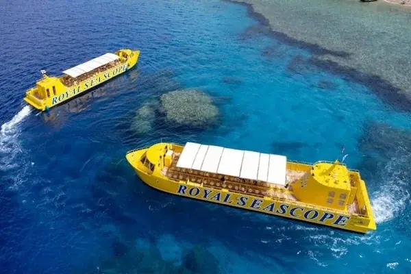 Aerial view of two yellow Royal Seascope boats navigating around a coral reef patch in turquoise water