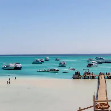 White speedboat with a black canopy top drifting on calm turquoise water with distant boats on the horizon