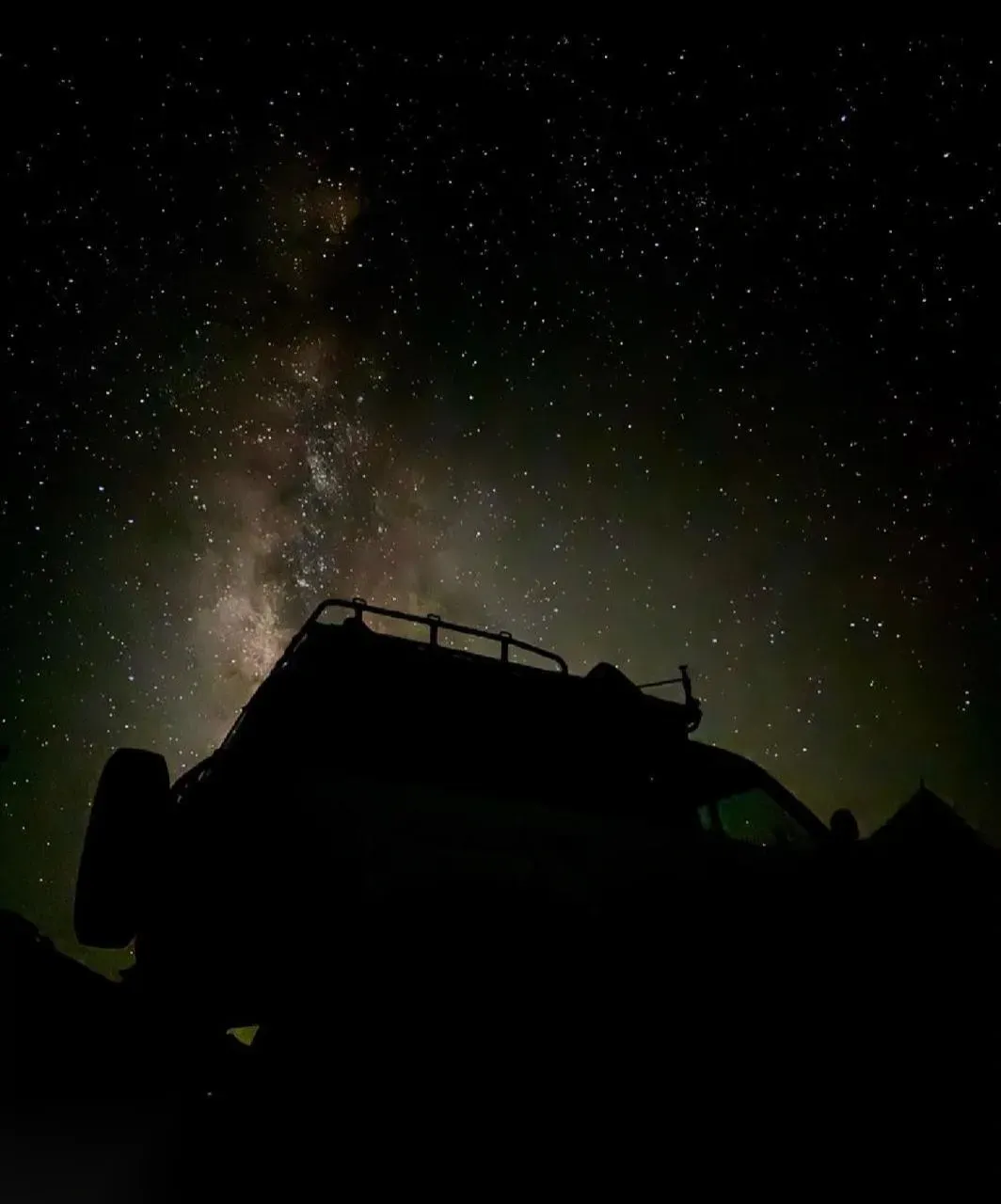 Silhouette of a safari 4x4 roof rack against a star-filled night sky showing the Milky Way over the desert