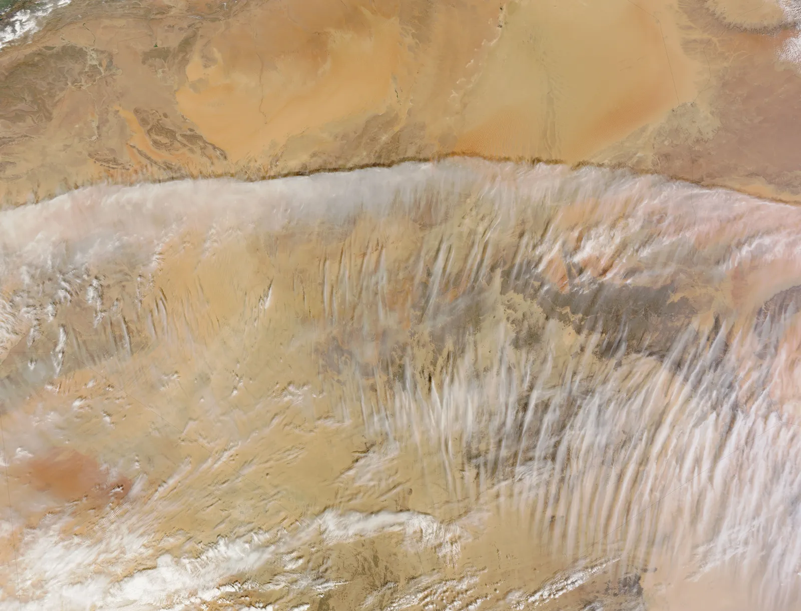 Silhouetted panorama of White Desert rock formations and hills against a vivid orange and pink sunset sky